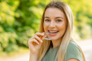 a patient smiling and holding their Invisalign aligner