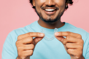 a patient smiling and holding their Invisalign aligner