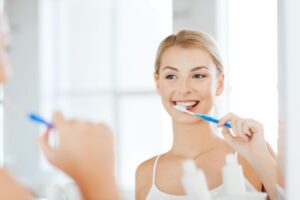 a patient brushing their teeth and smiling